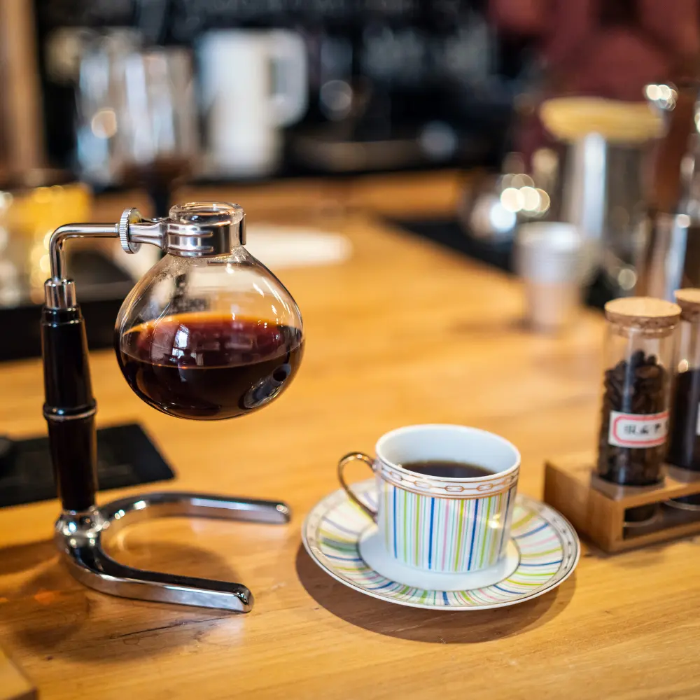 siphon brewing next to a coffee cup