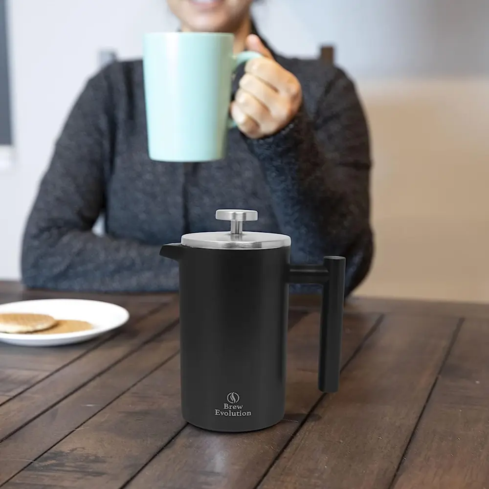 woman enjoying a cup of coffee with a press near by