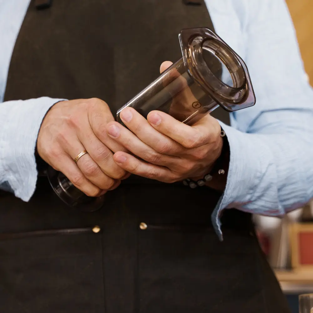 barista handling aeropress coffee maker