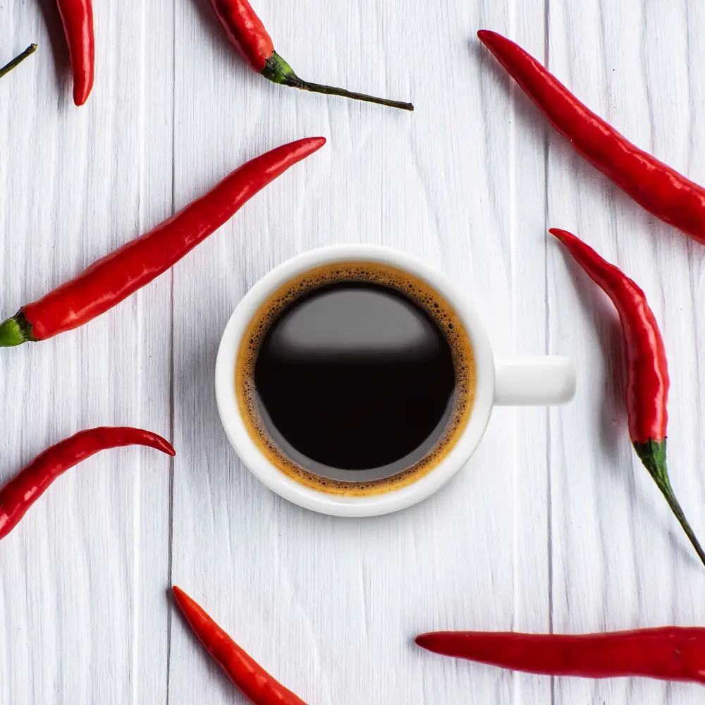 cup of black coffee with red hot chili peppers