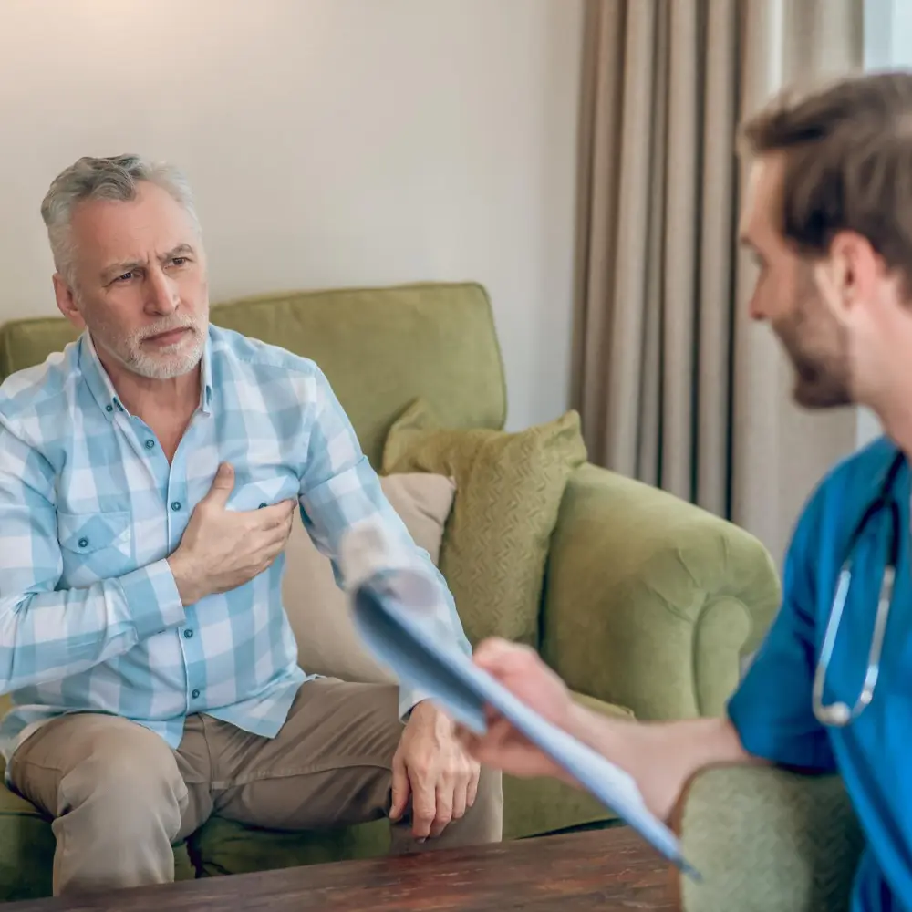 man talking to a doctor while holding his chest