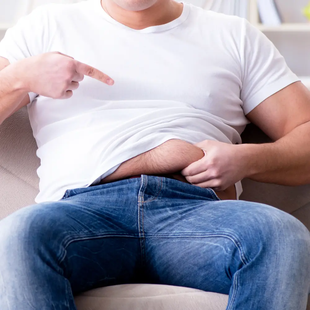 a man grabbing his belly fat while pointing to it