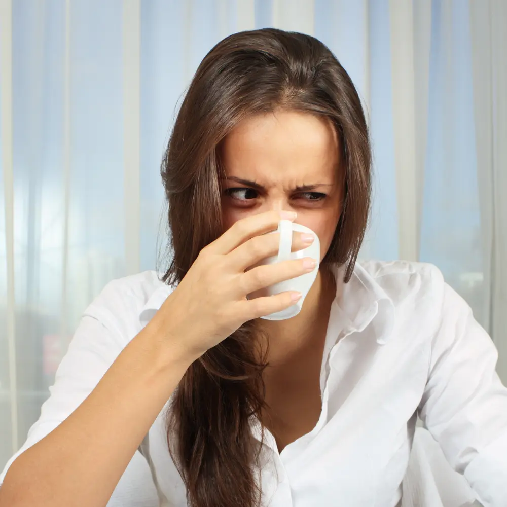 woman sipping her coffee with an expression of digust