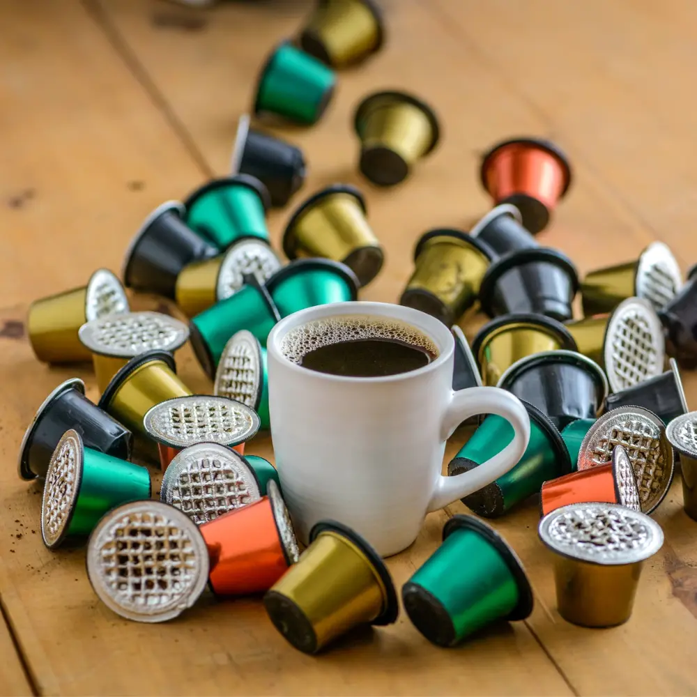 various used coffee capsules with a mug of fresh black coffee