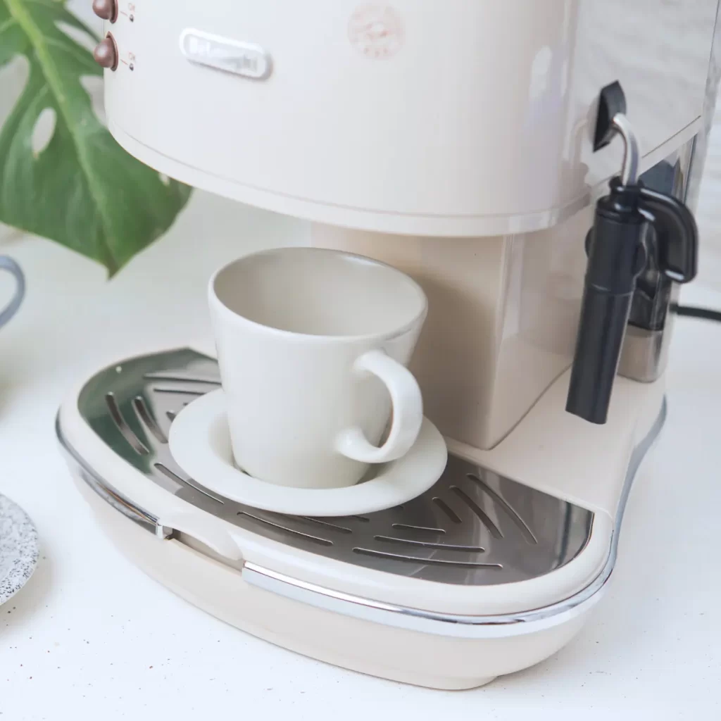 a white coffee maker with a cup on it