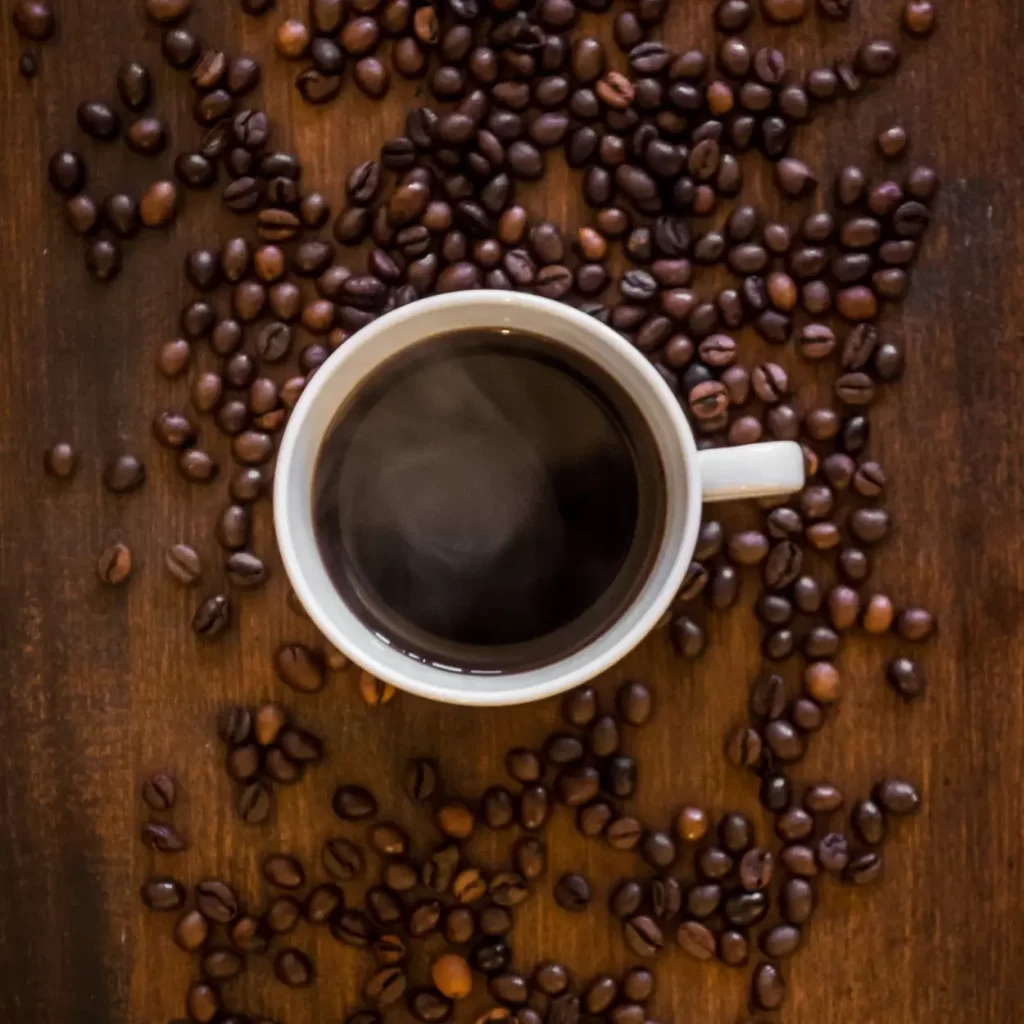 black coffee in a white mug with beans