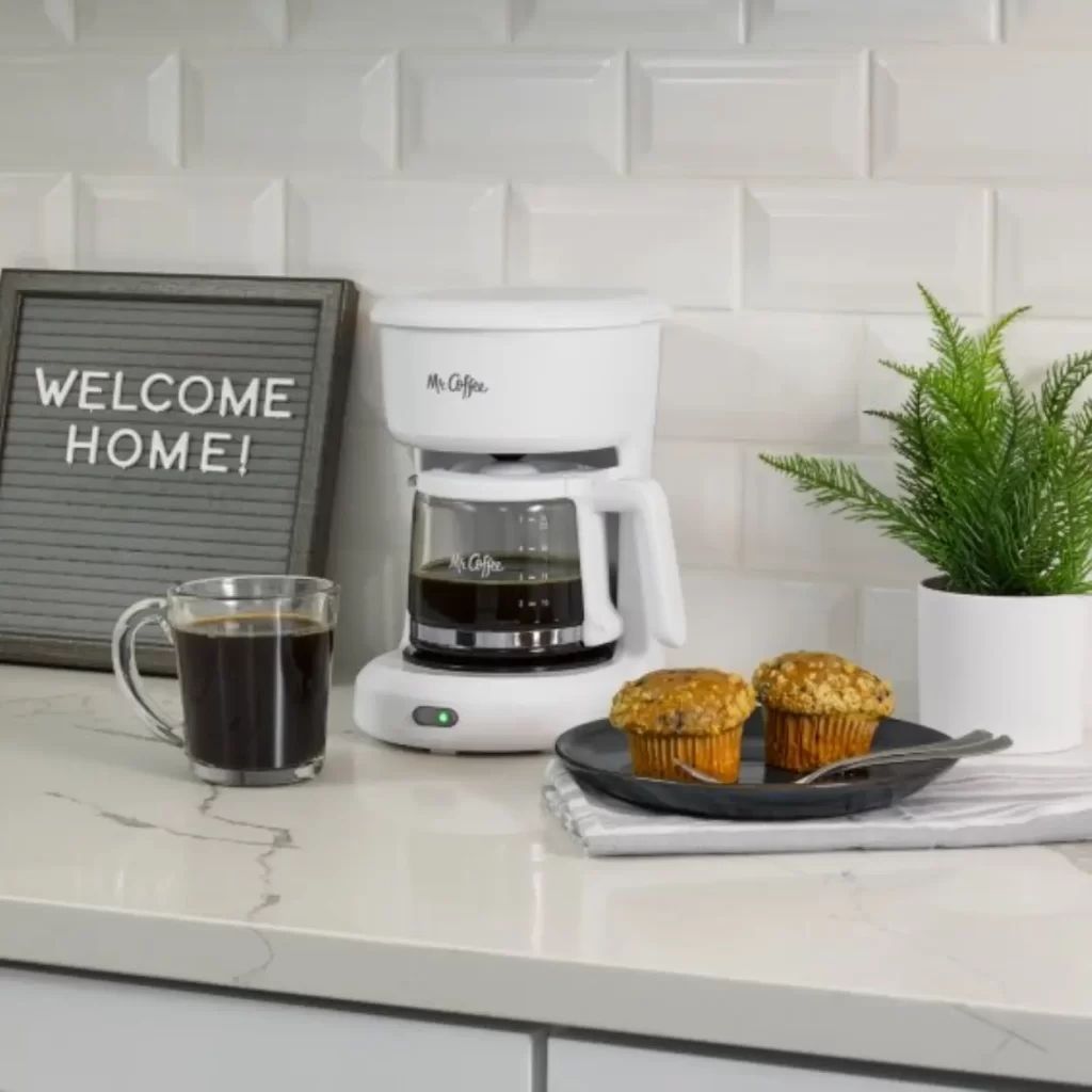 white coffee maker with a cup of coffee and muffins