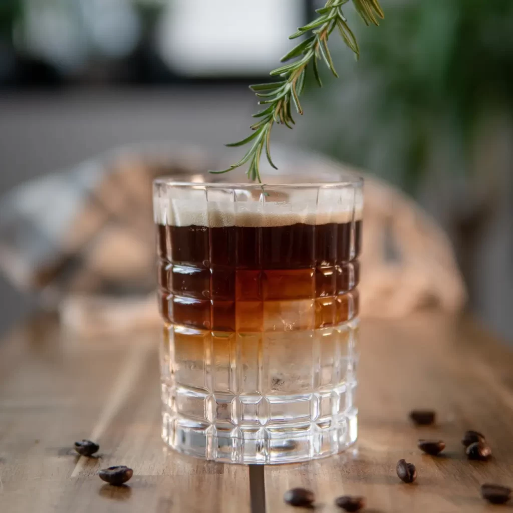a glass with a coffee and a branch of a plant
