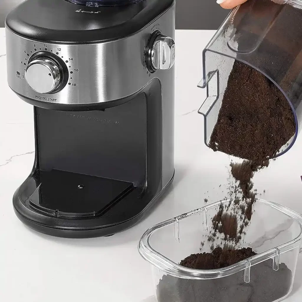 a coffee maker and hand pouring ground coffee into a container