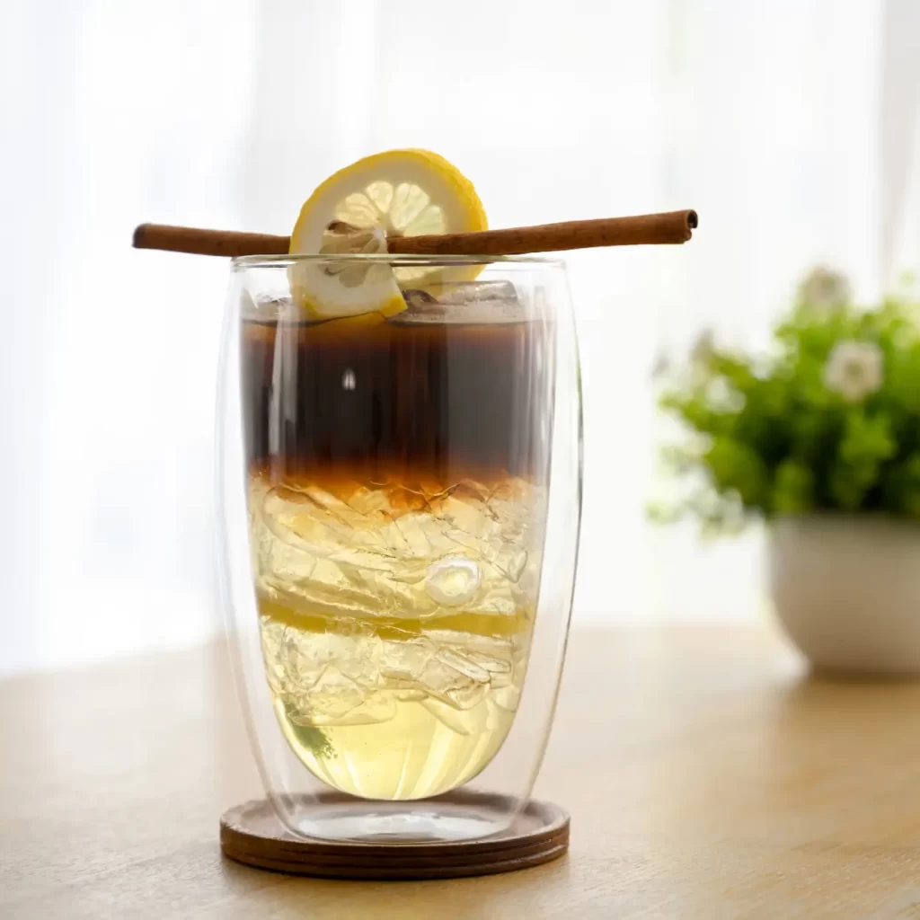 a glass with a coffee and a slice of lemon on it