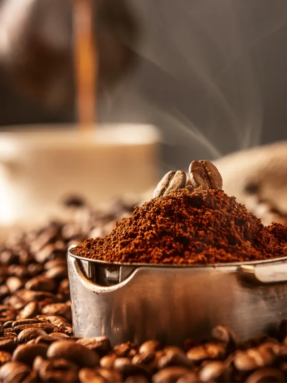 a cup of coffee with coffee beans and a pile of ground coffee