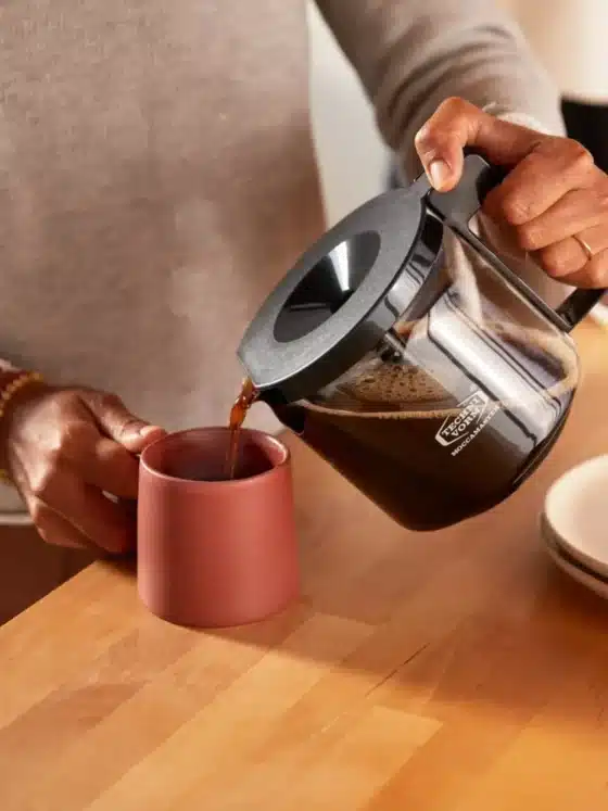 a person pouring drip coffee into a mug