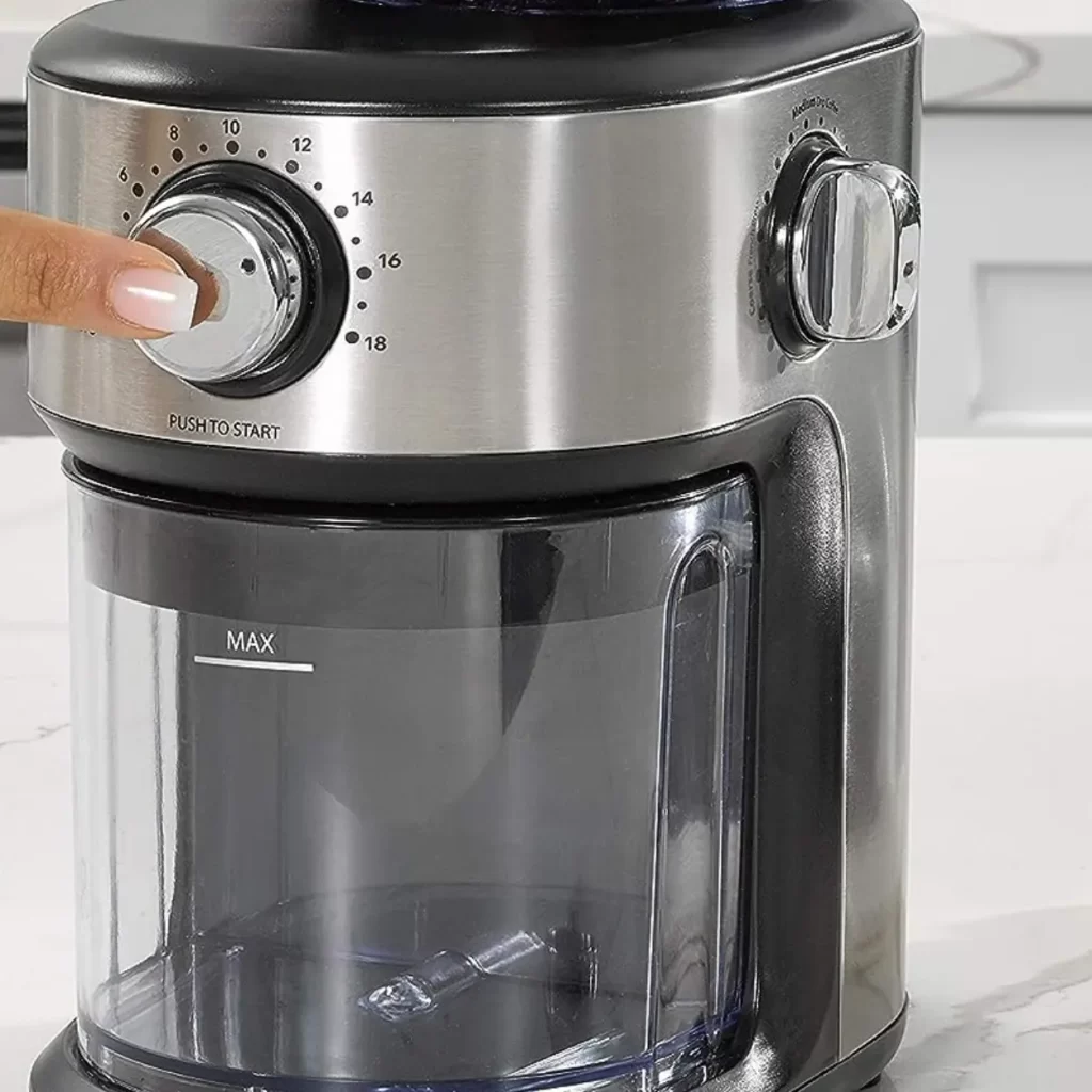 a hand pressing a button of a burr grinder