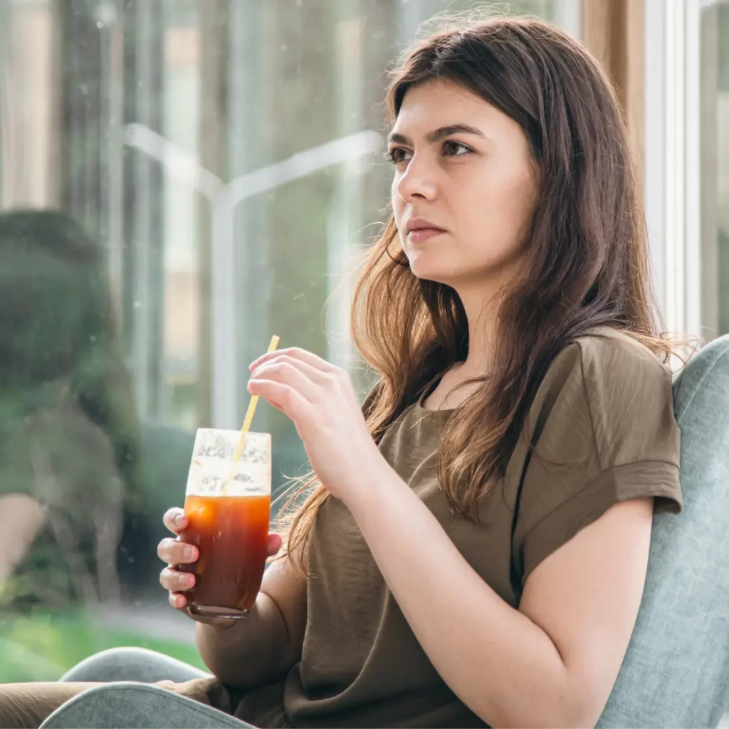 a woman sitting in a chair drinking espresso tonic