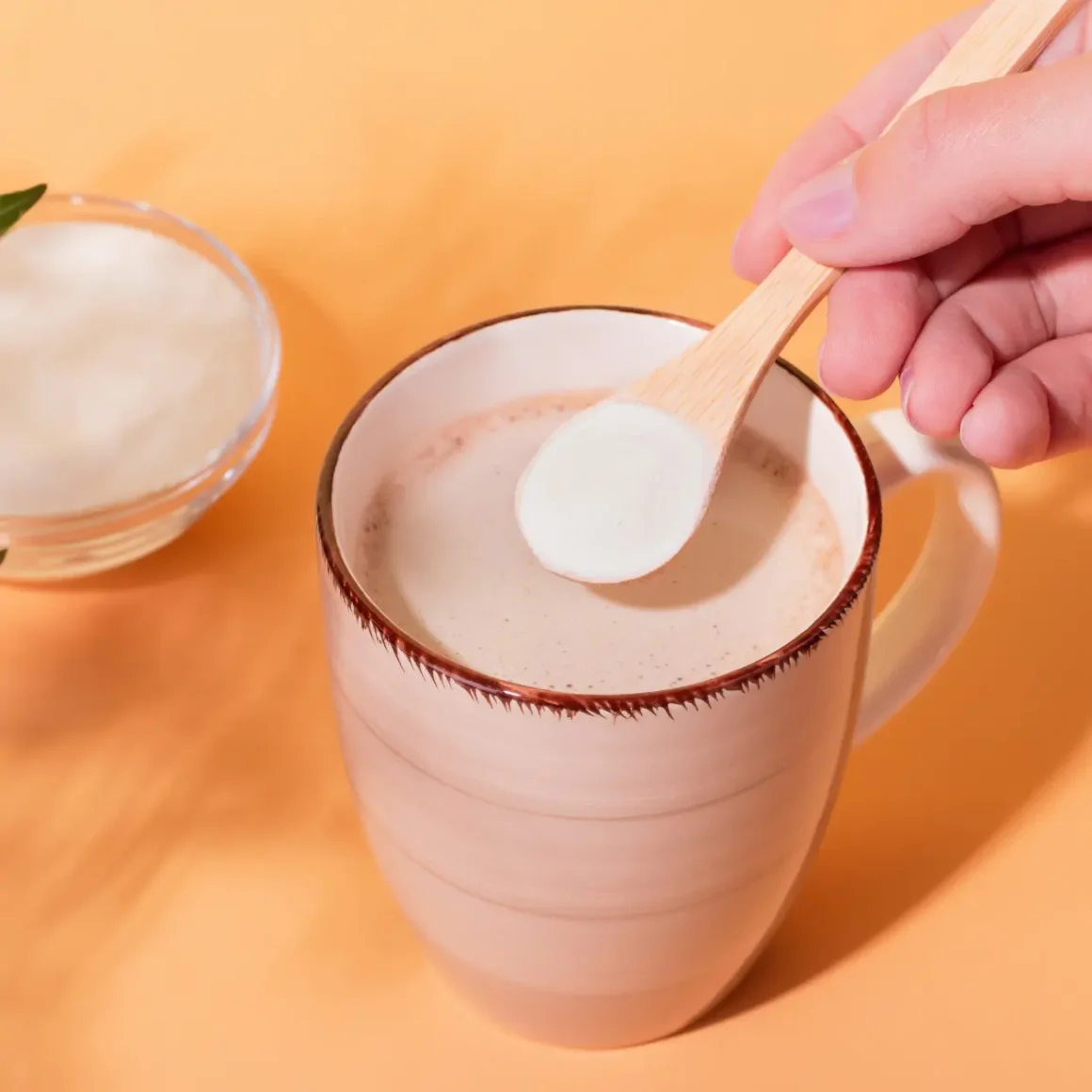 a person holding a spoon of sugar over a cup of joe
