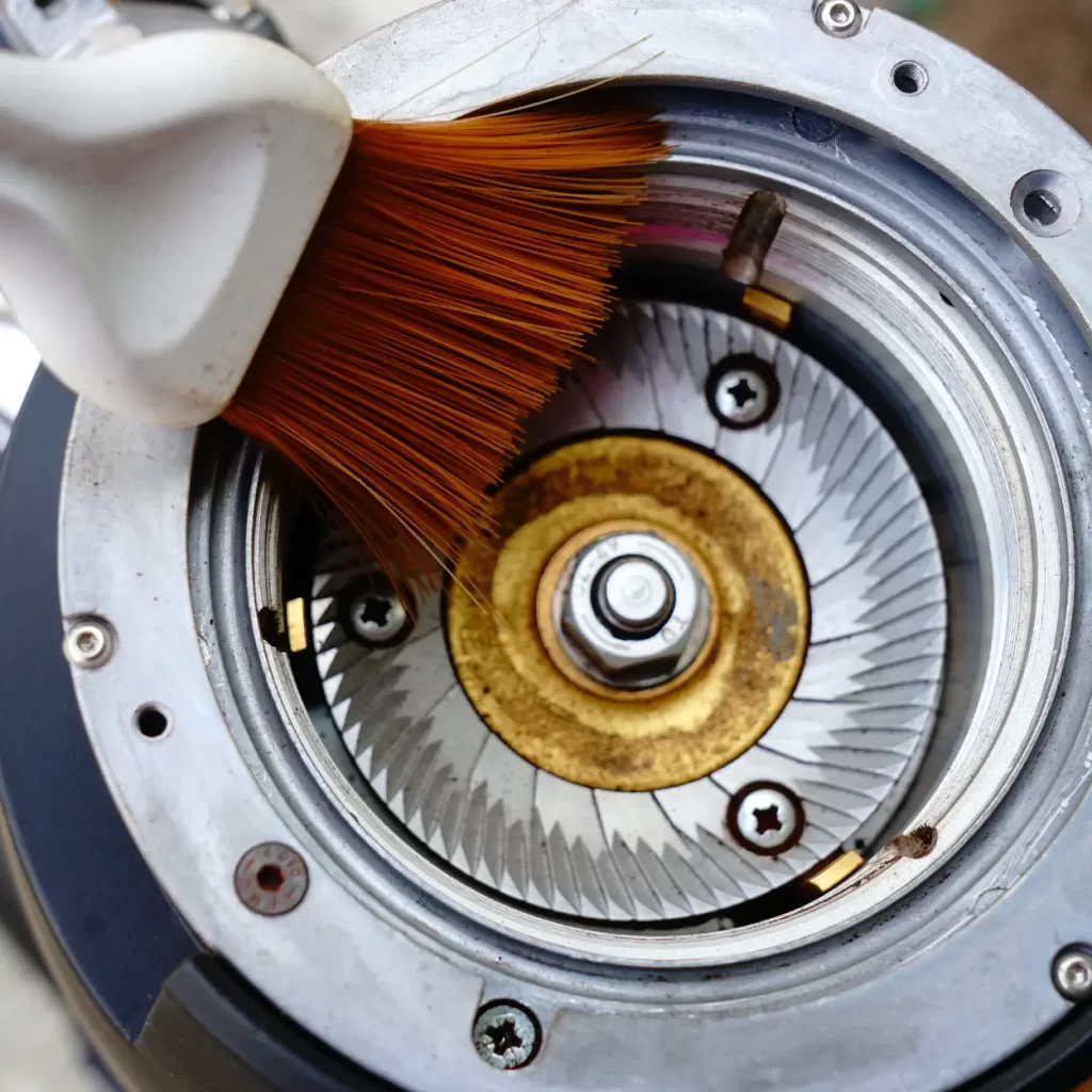 a brush cleaning a coffee grinder