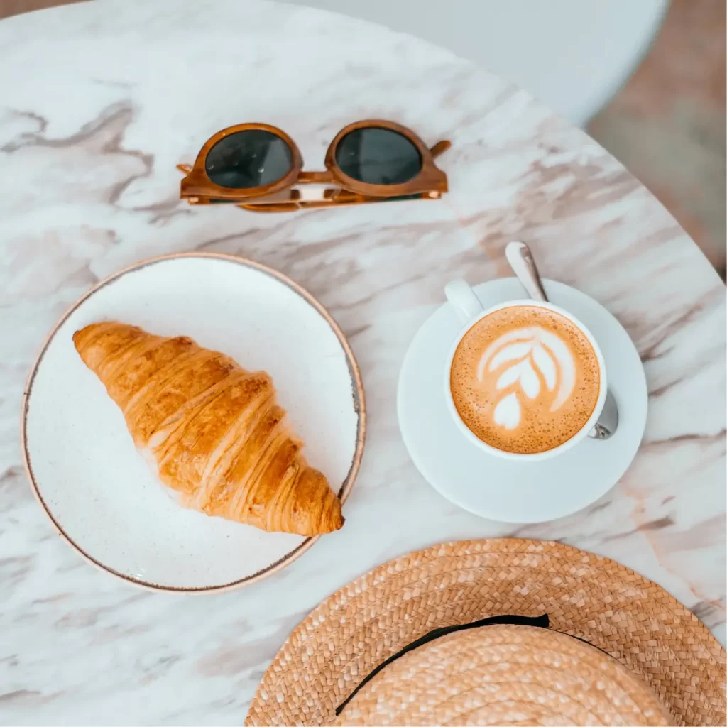 a croissant and a cup of coffee on a marble table
