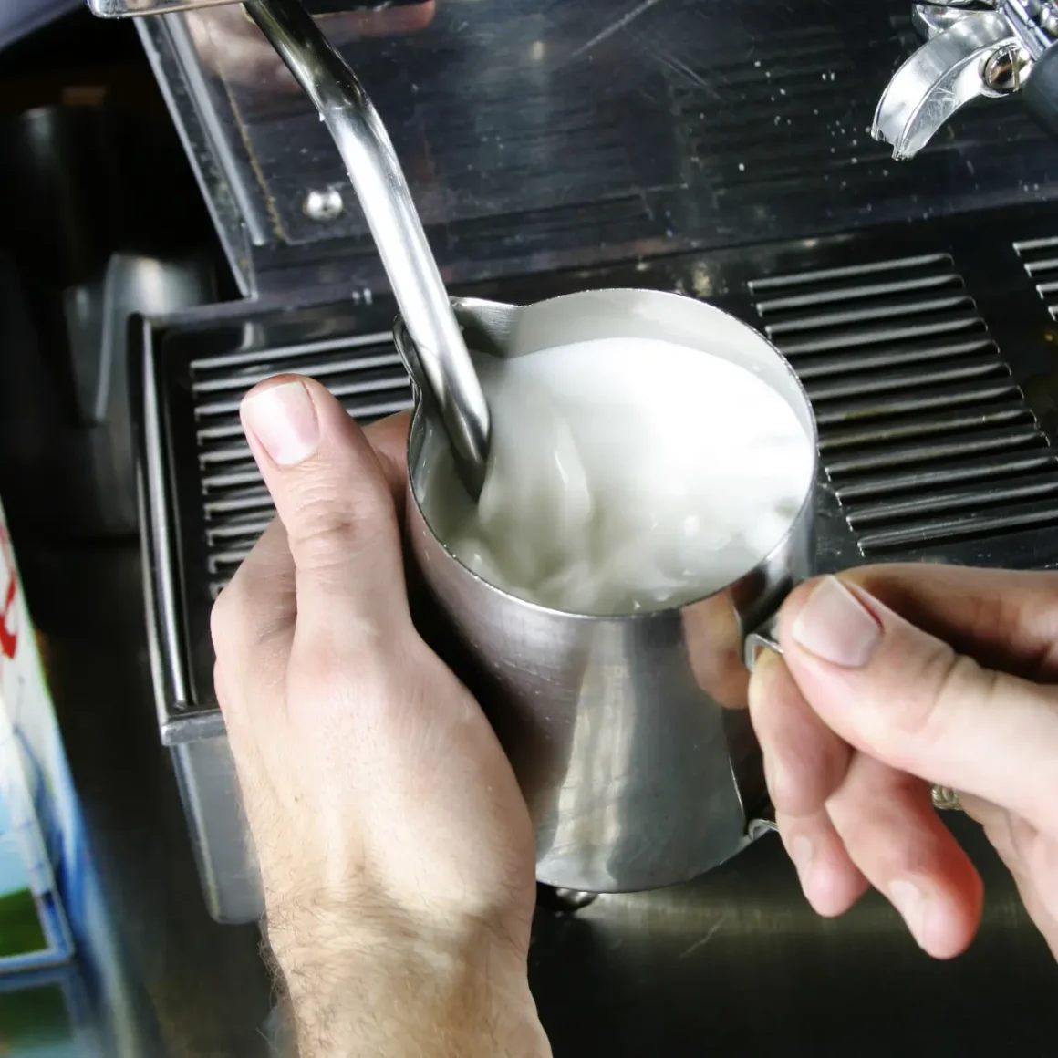 a person pouring milk into a cup