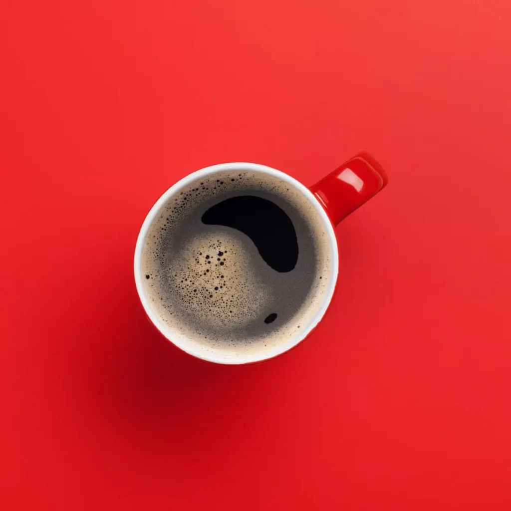 a cup of coffee on a red surface