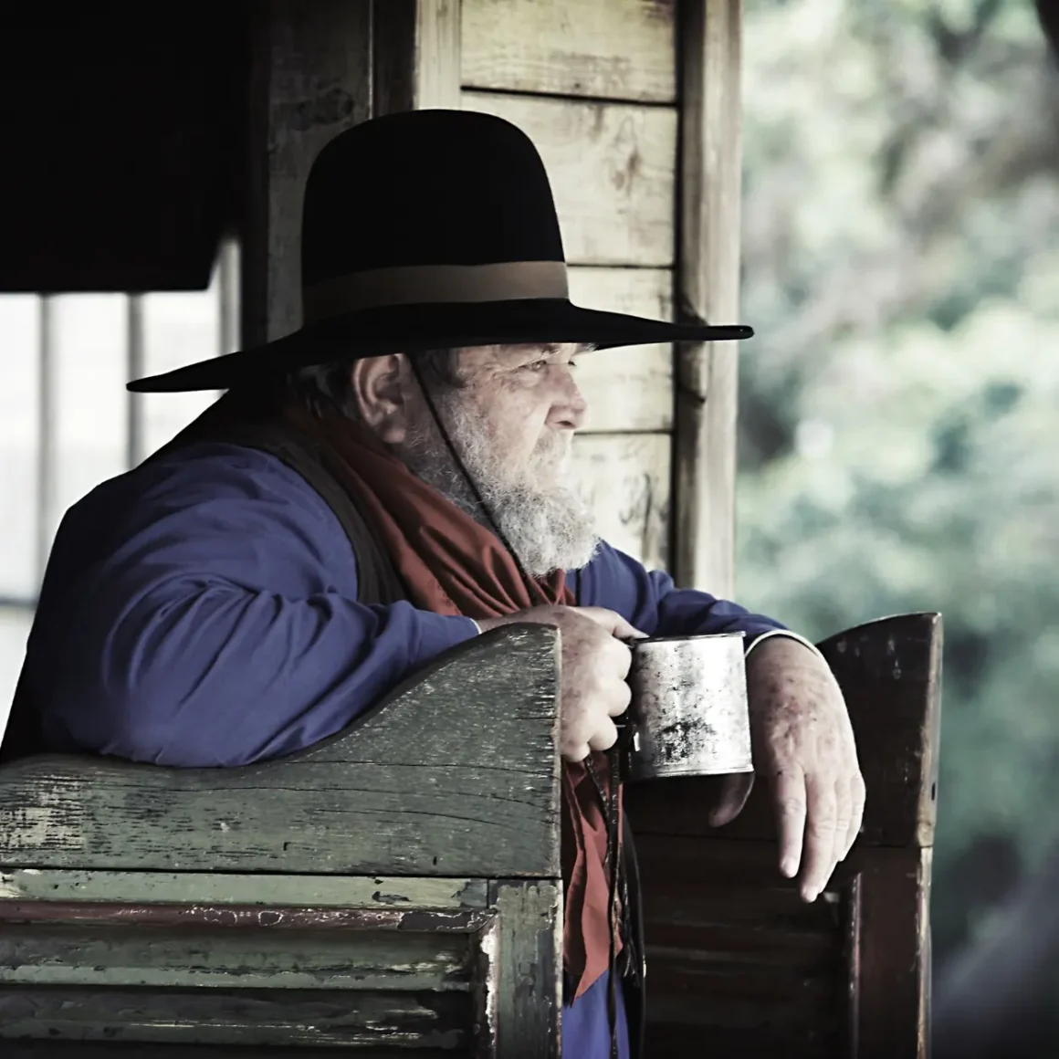 a person in a hat and scarf sitting on a chair holding a cup