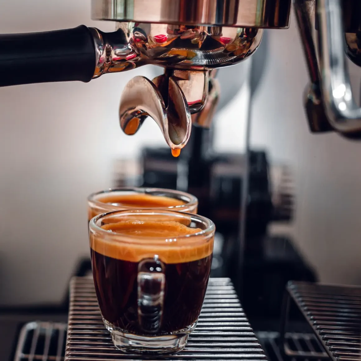 espresso machine pouring coffee into two demitasse cups