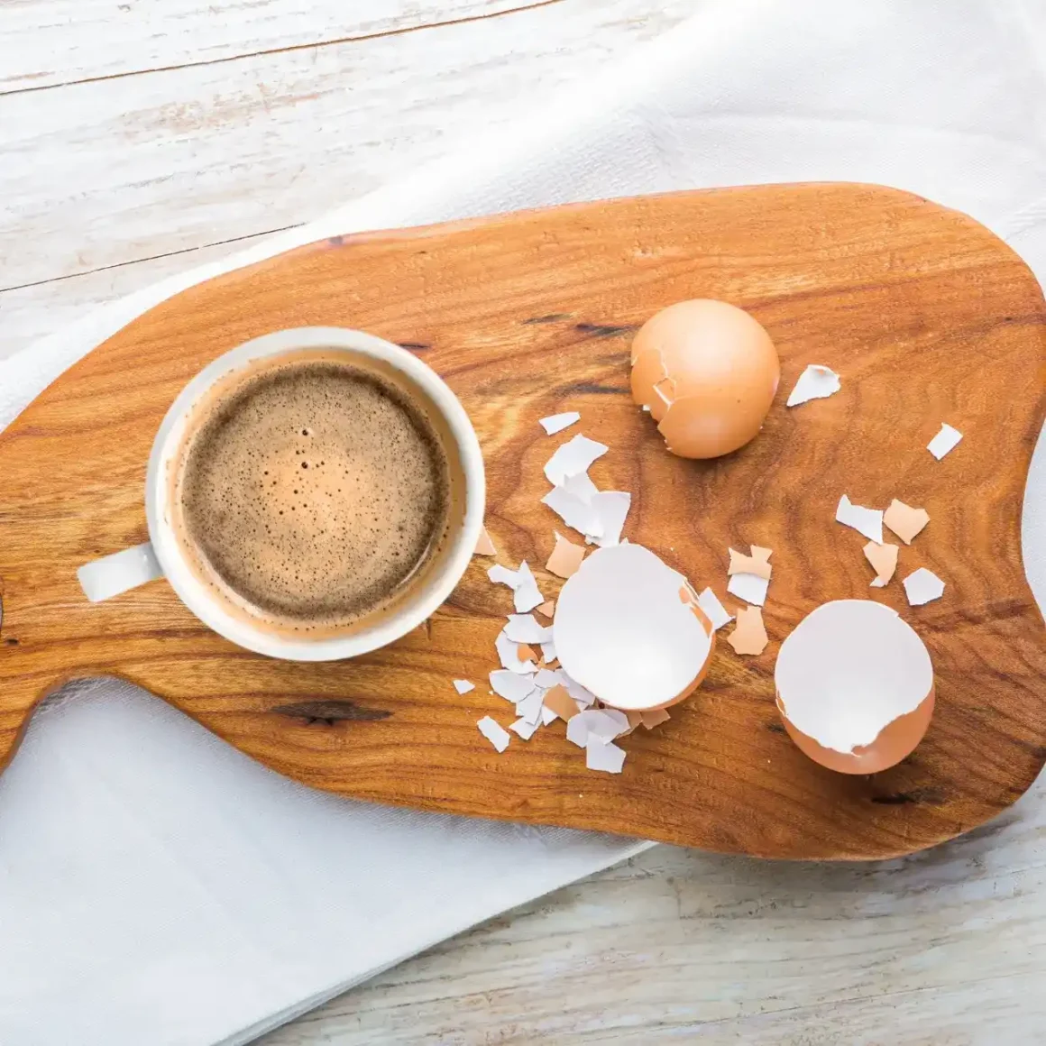 a coffee and eggs shells on a cutting board