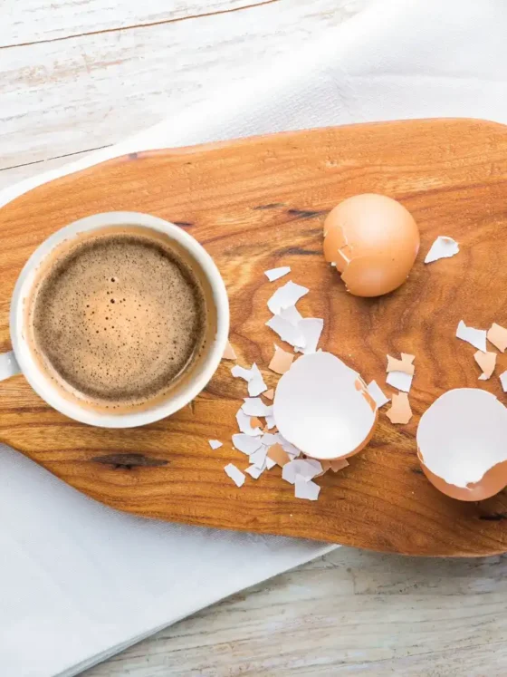 a coffee and eggs shells on a cutting board