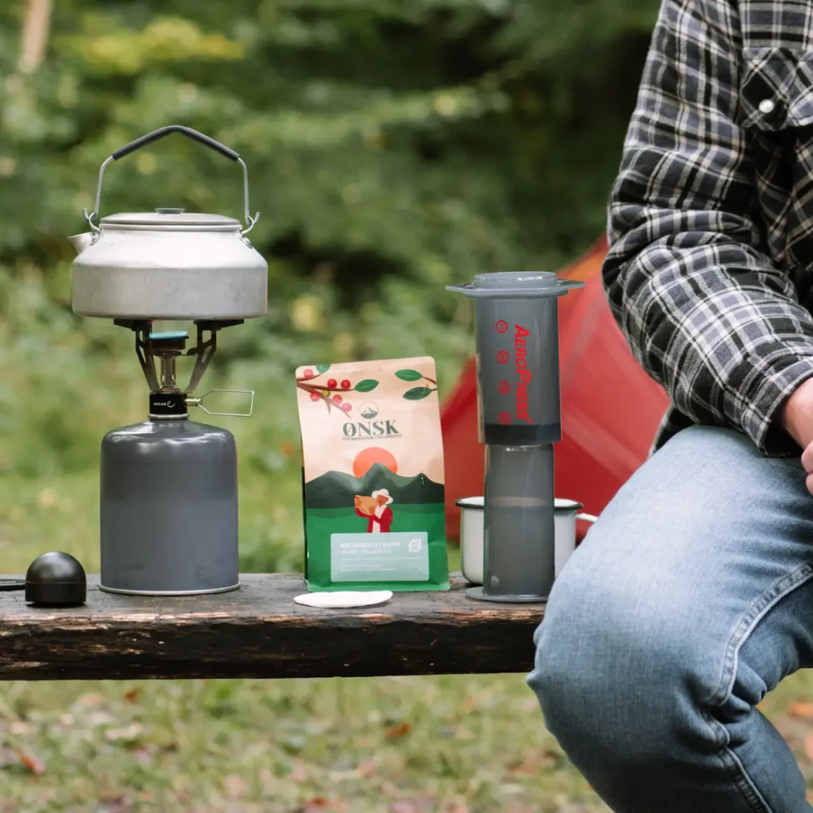 a person sitting on a bench with a kettle and a bag of coffee