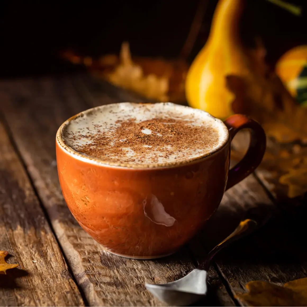 a cup of apple cider espresso with a spoon and leaves