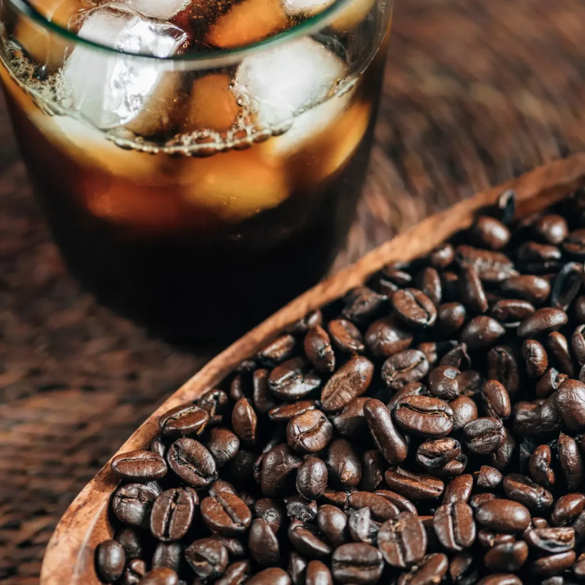 a bowl of coffee beans and ice and coffee in a glass