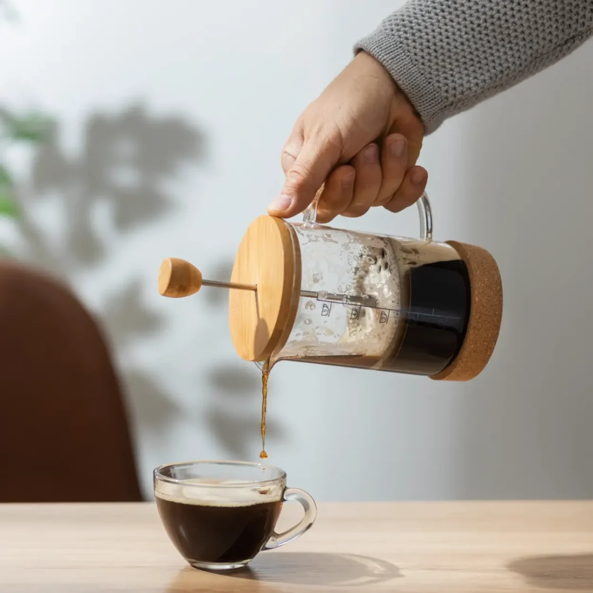 a person pouring french press single origin coffee into a cup