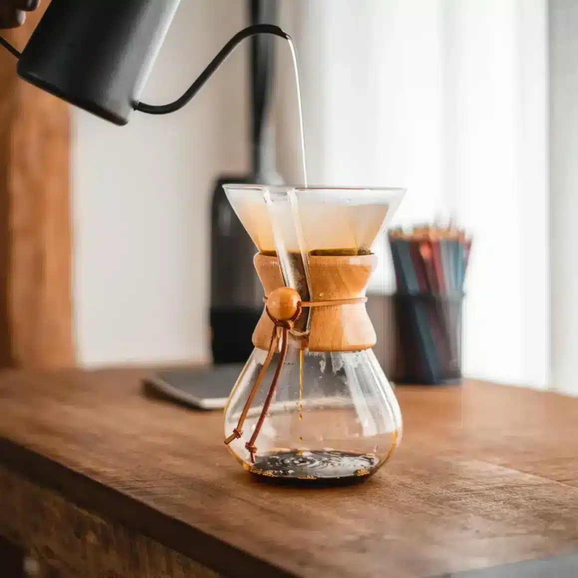 a hand pouring liquid into a glass container