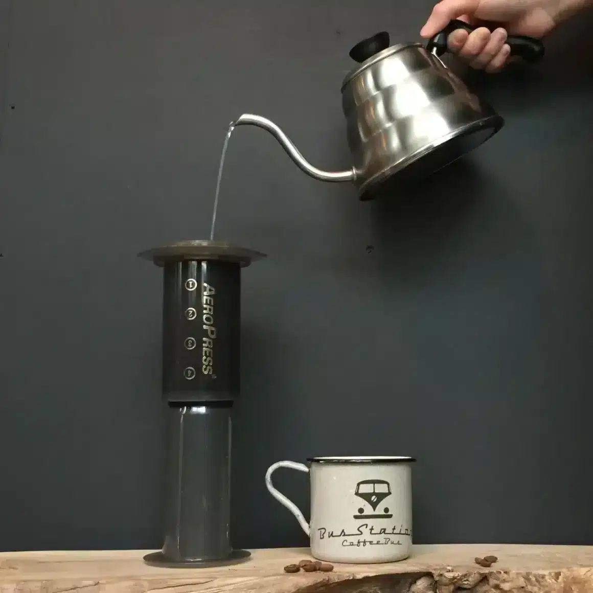 a hand holding a kettle pouring water into a coffee machine
