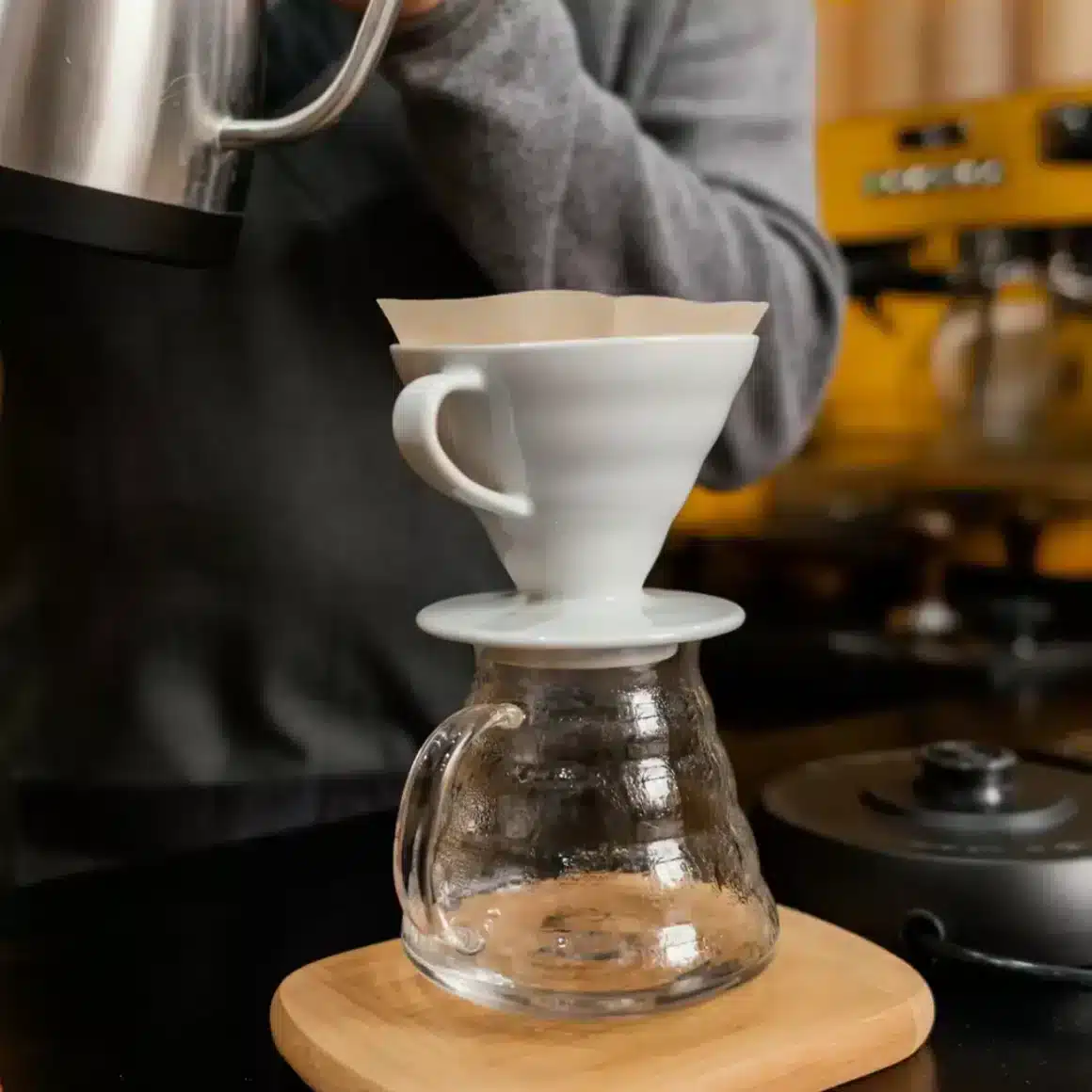 a person pouring a coffee into a glass dripper