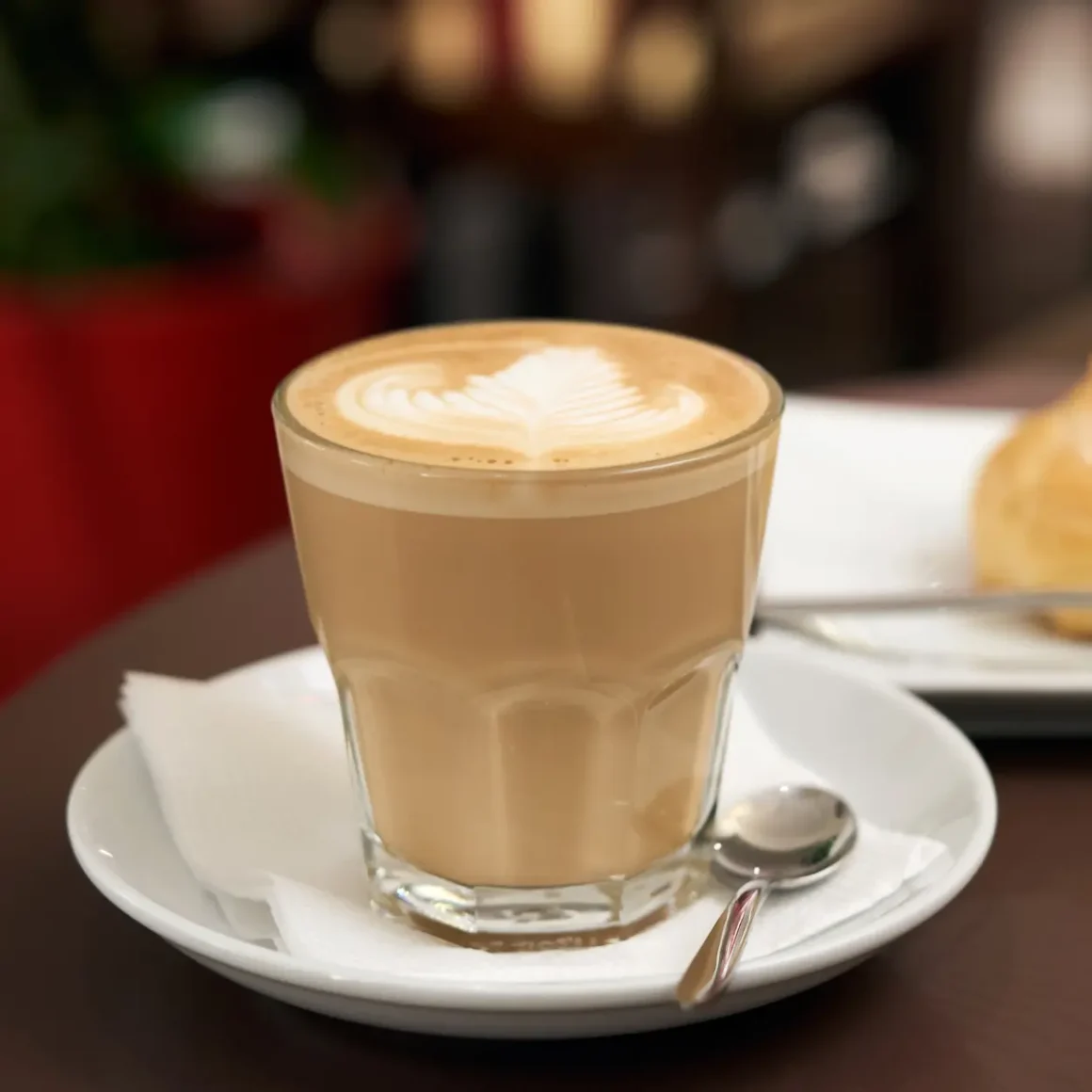 a glass of latte with a heart shaped foam on top of it