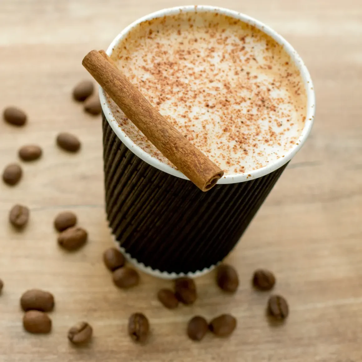 a cup of instant coffee with cinnamon stick and coffee beans