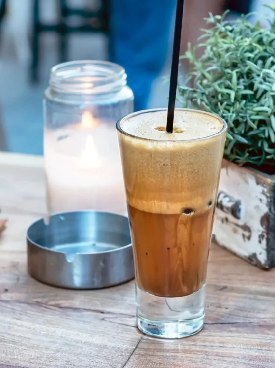 a glass of freddp cappuccino with a straw in it