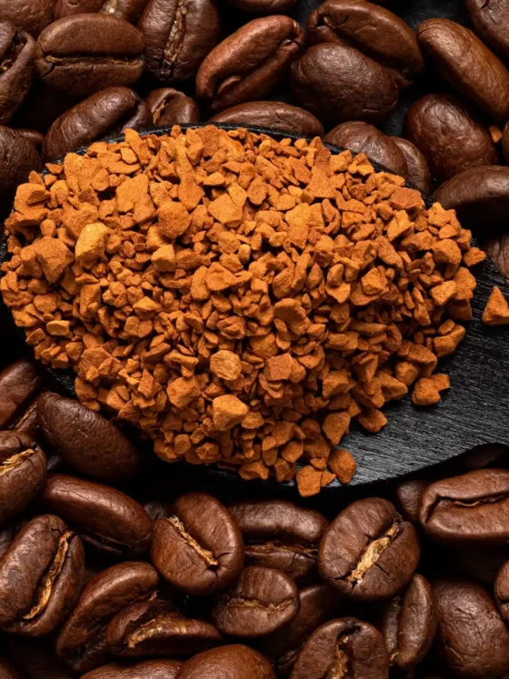 a spoon full of coffee granules over the pile of coffee beans
