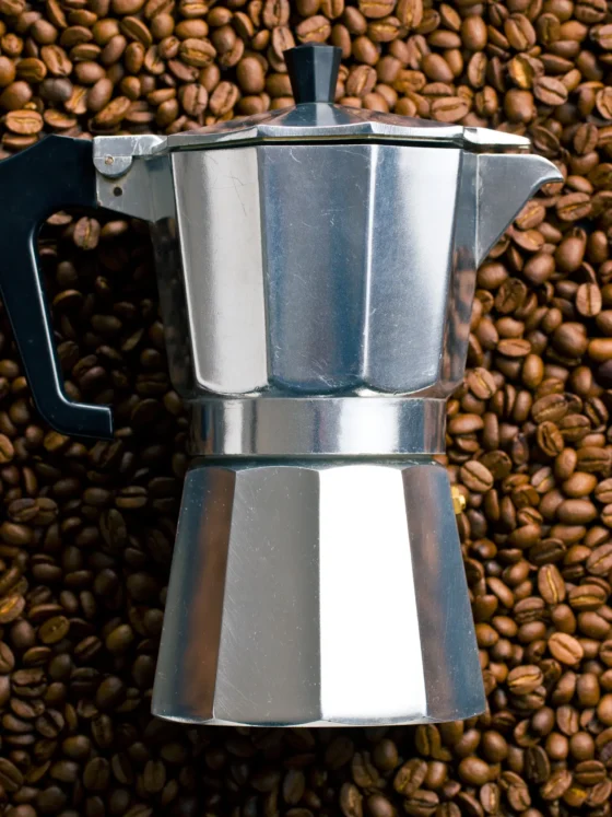 a coffee maker on a pile of coffee beans