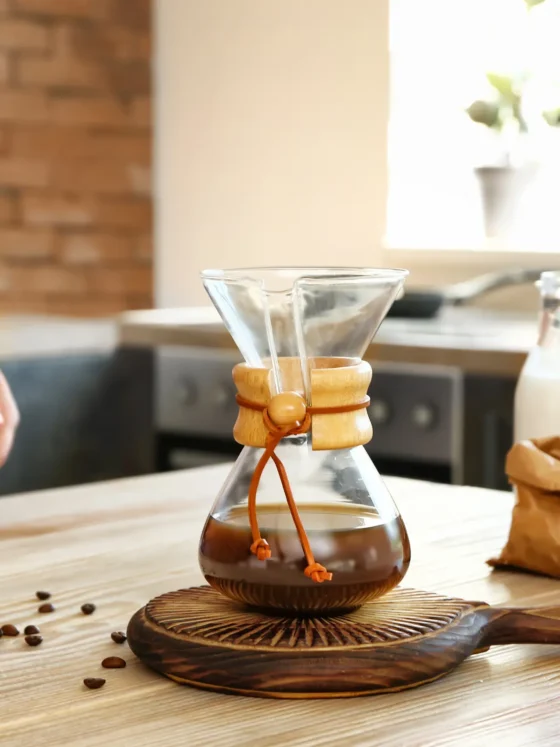 a glass container with coffee on a wood surface