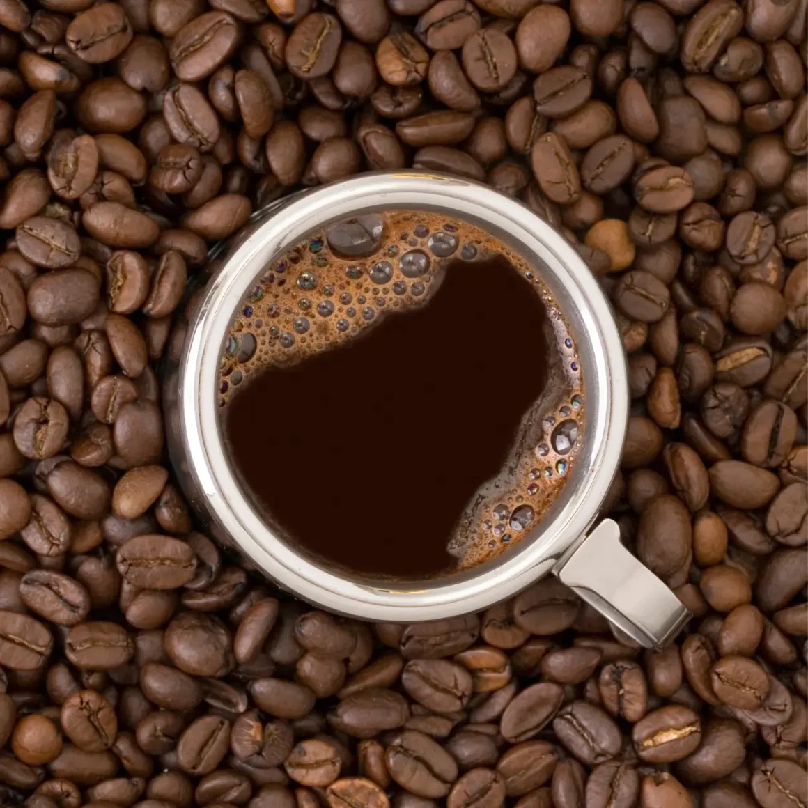 a cup of coffee on a pile of coffee beans