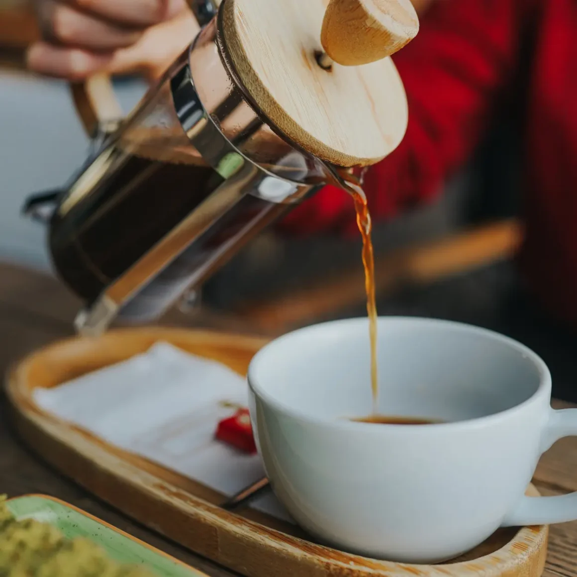 a person pouring coffee from a french press into a cup