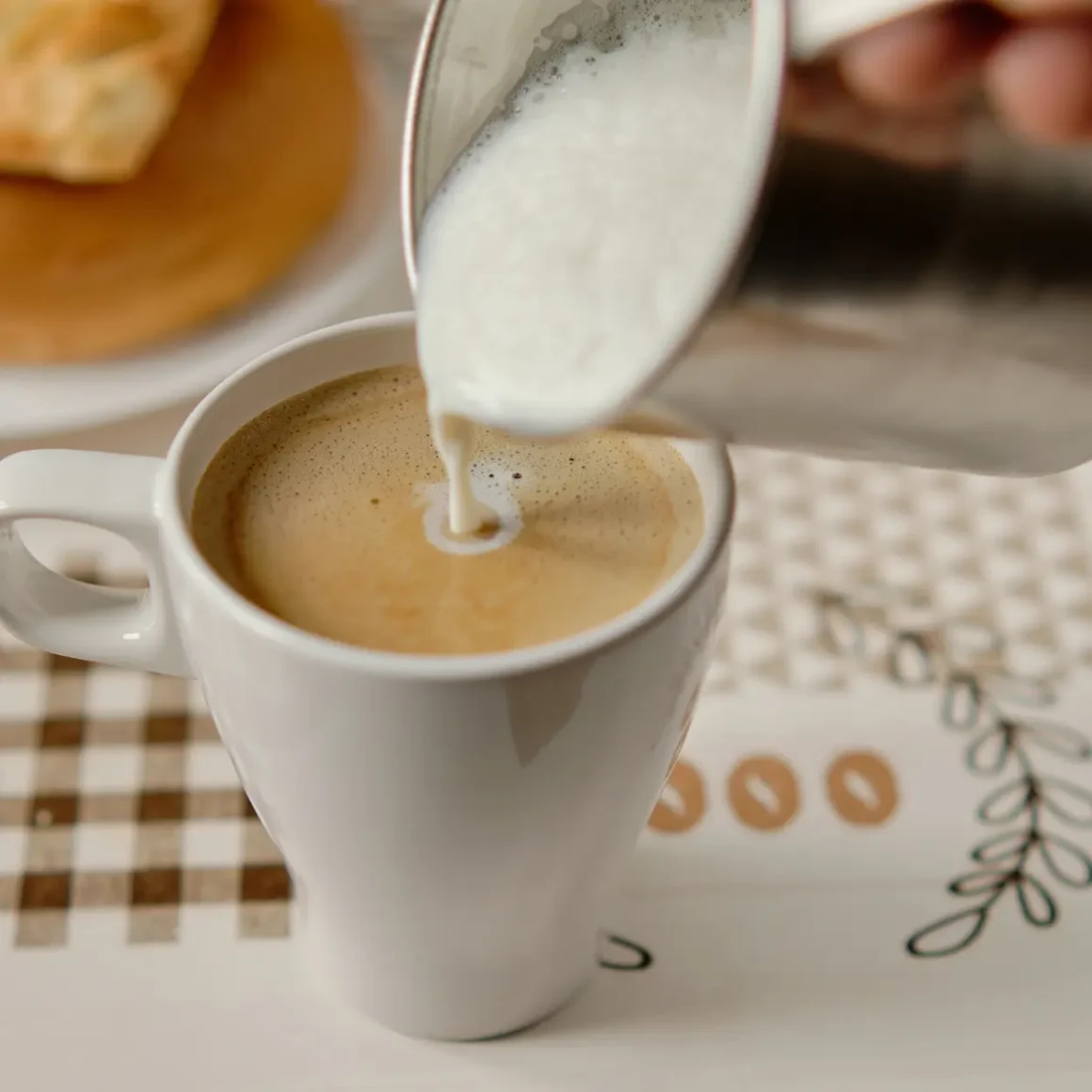 a person pouring milk into a cup of instant coffee