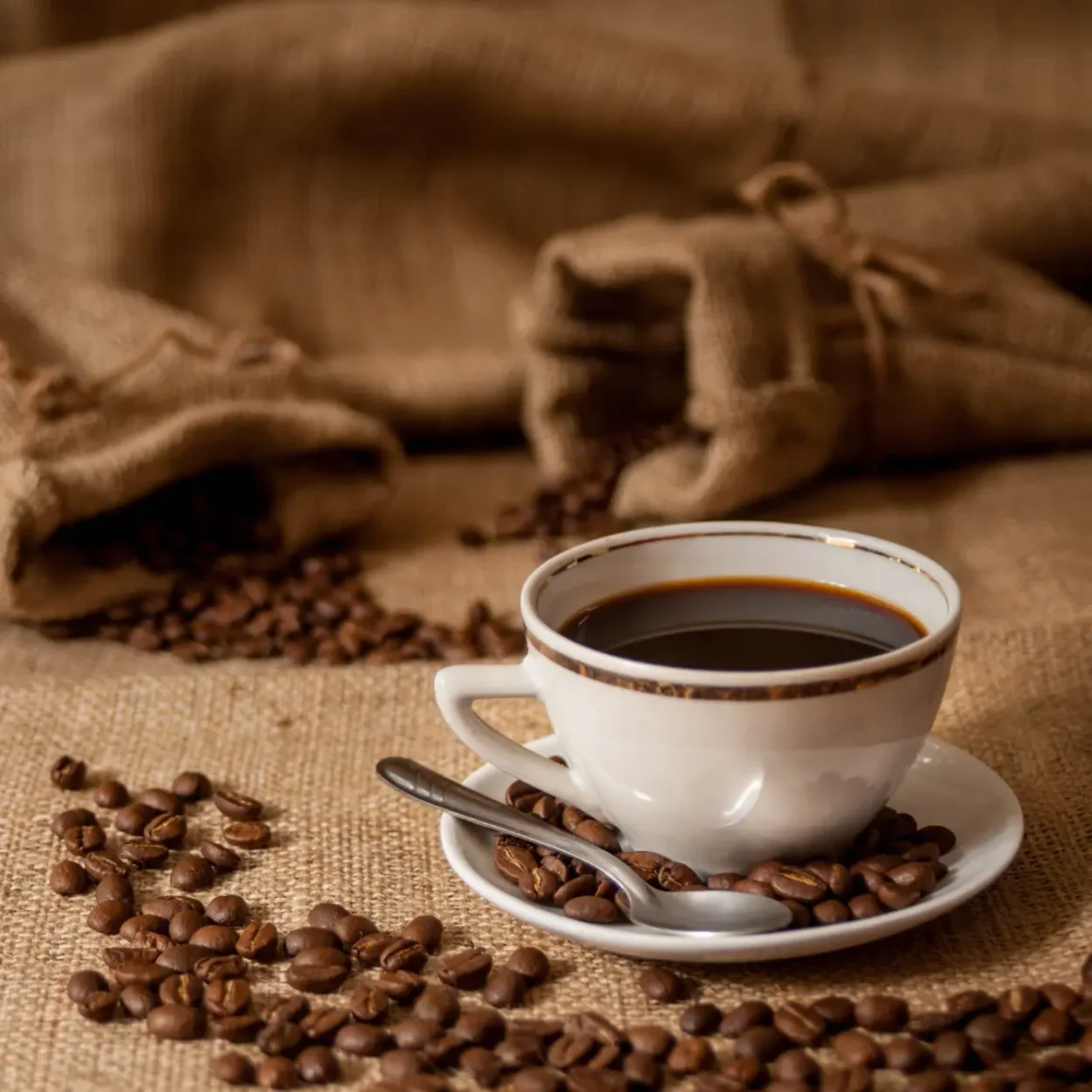 a cup of single origin coffee on a saucer with coffee beans