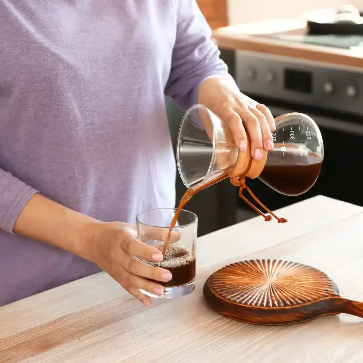 a person pouring coffee into a glass