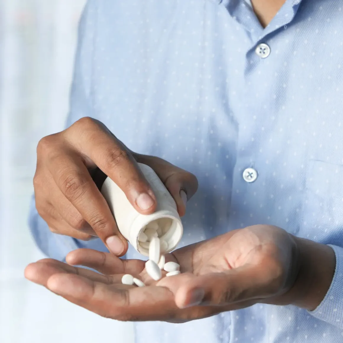 a person pouring pills into their hand