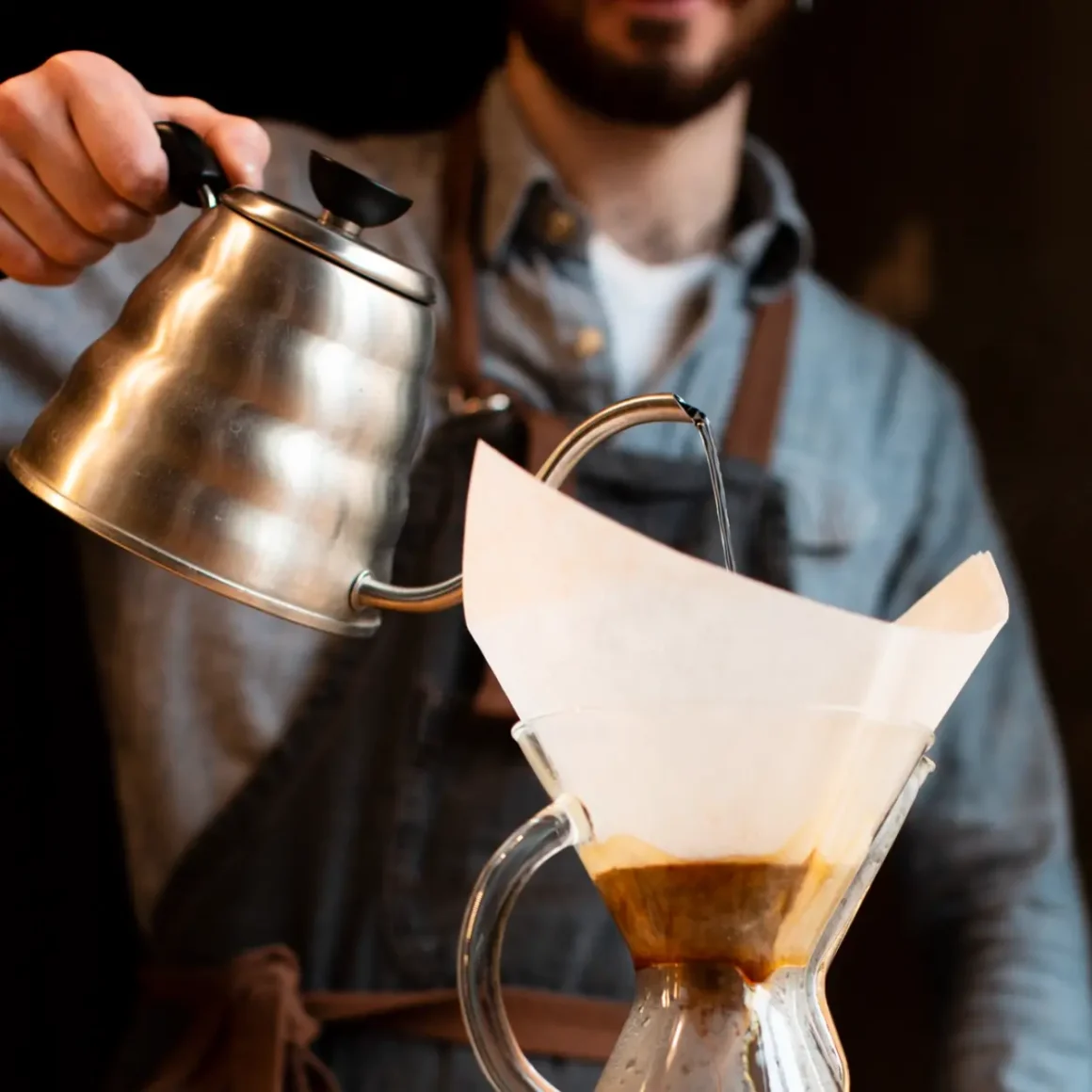 a person pouring water into a glass container