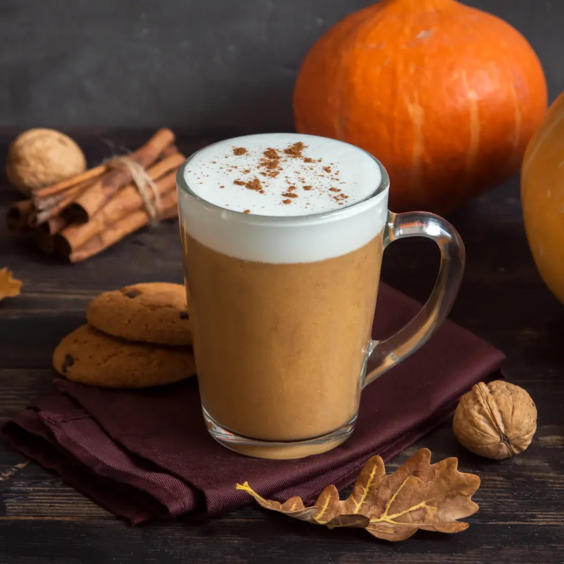 a glass mug of pumpkin spice latte with a foamy foam on top of it