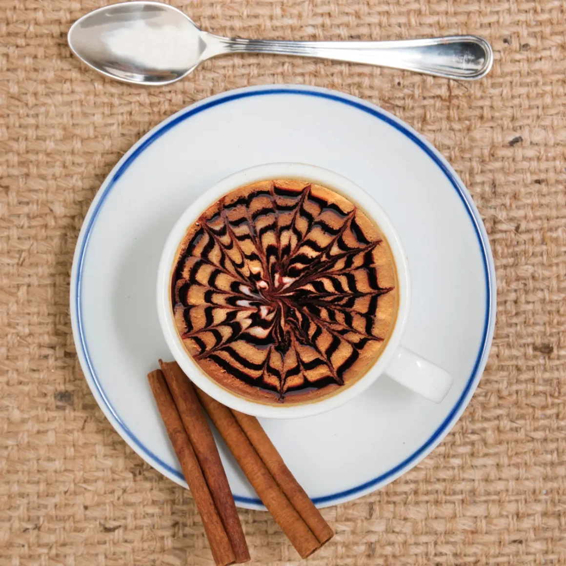 a cup of spiced mocha with cinnamon sticks and a spoon