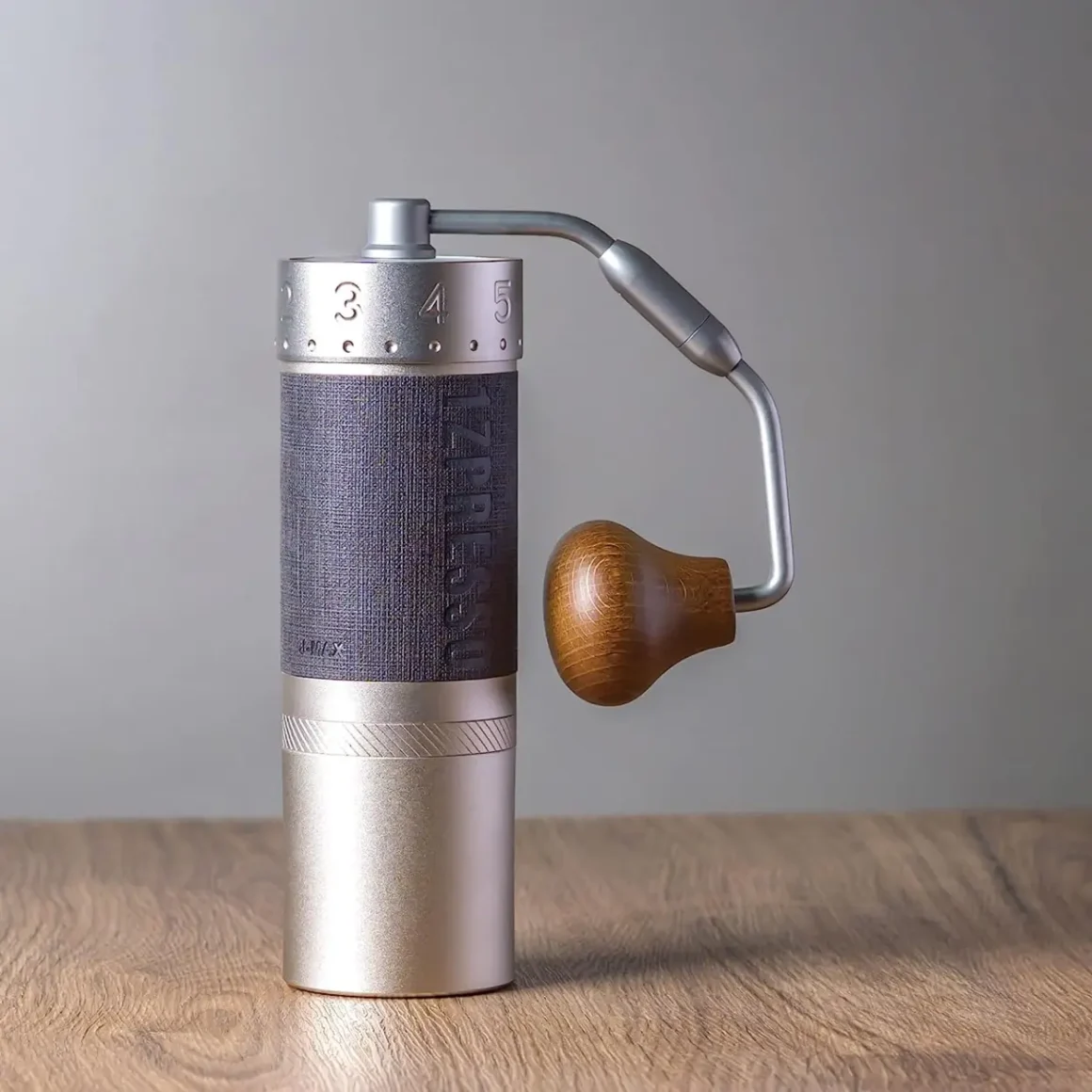 a 1zpresso j-max s manual coffee grinder on a wooden surface